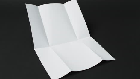 video of piece of white paper with creases on black background