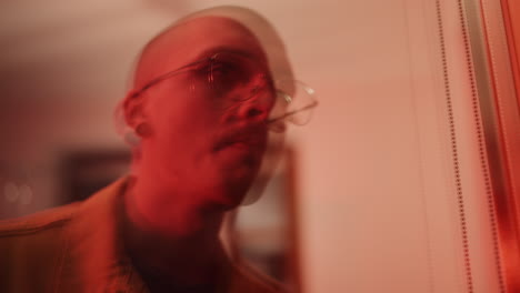 close-up portrait of a man with glasses under red light