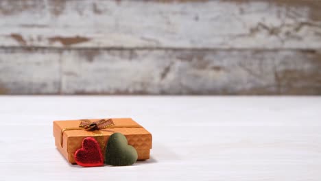 caja de regalo dorada con forma de corazón rojo y verde en superficie blanca 4k