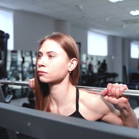 beautiful woman with strong hands raises barbell in a fitness club on the background of sports equipment. blurred background. close-up