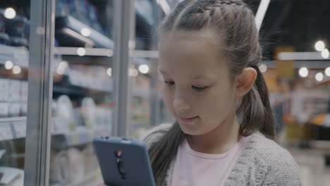girl using phone in supermarket