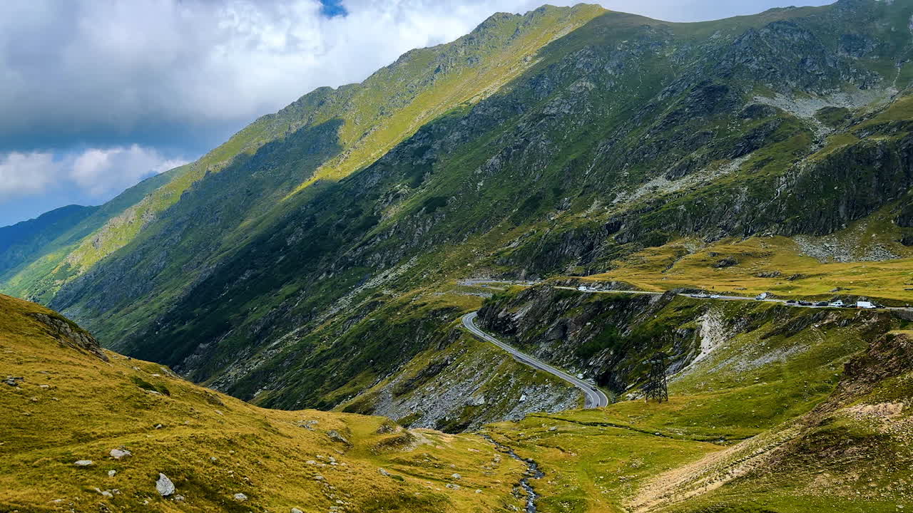 Montagne maestose con cielo nuvoloso. Auto parcheggiate lungo la strada con vista sul paesaggio. I Monti Carpazi, Romania