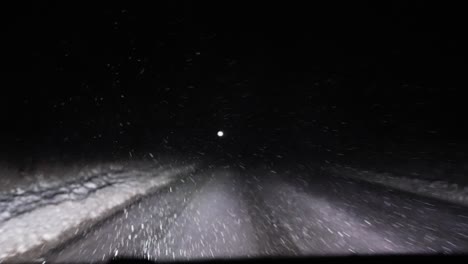 slow motion snow falling while driving through snow storm with white dusted roads at night