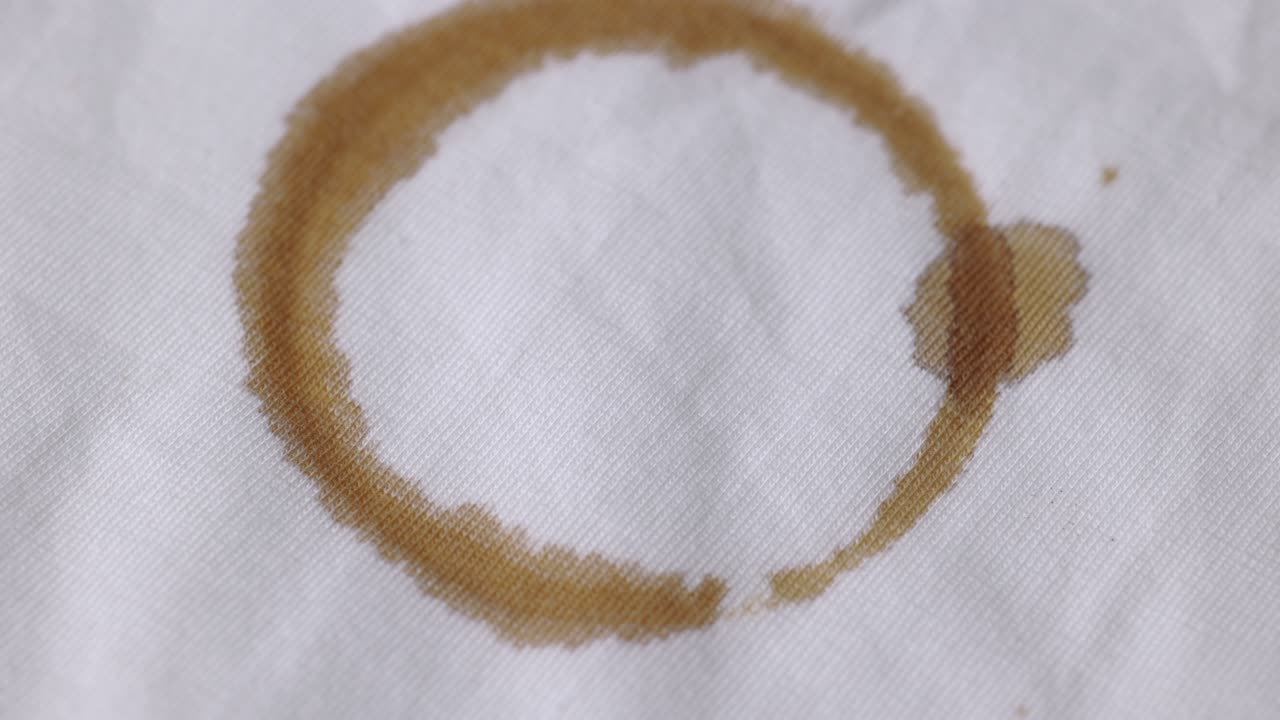 A white cotton shirt stained with brown coffee stains. Must be washed thoroughly in the washing machine