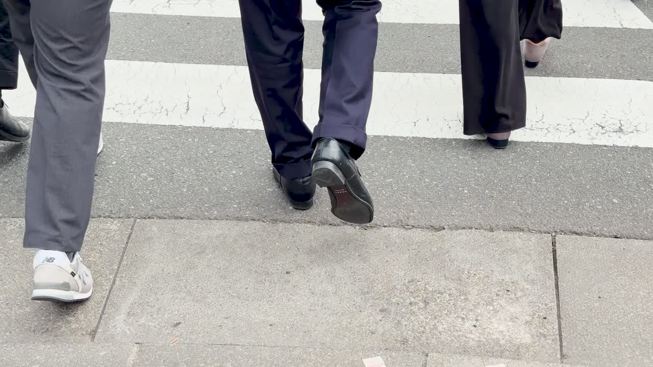 Low angle shot of business professionals walking across a pedestrian crosswalk on a city street