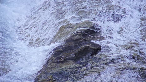 A-High-Angle-Shot-Of-A-Rock-Being-Cast-By-A-Strong-Gush-Of-Sea-Waves-As-They-Flow-Endlessly