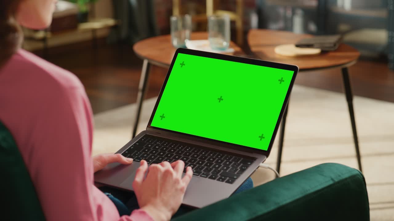 Young Adult Woman Working from Home Loft Apartment on Laptop Computer with Green Screen Mock Up Display. Creative Female Browsing the Web, Writing on Social Media. Close Up Over the Shoulder Footage.