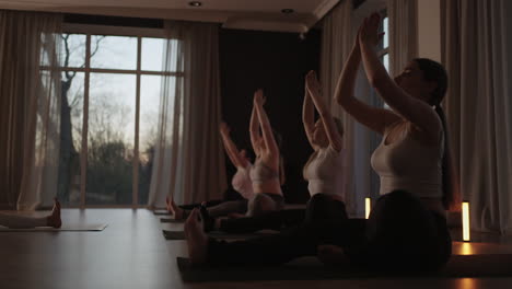 fitness club. female caucasian instructor coaching and adjust correct pose to caucasian girl student at front while others doing follow them.