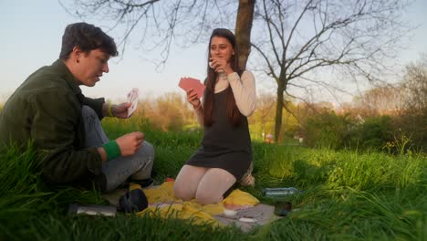 couple playing cards and enjoying a picnic in a park