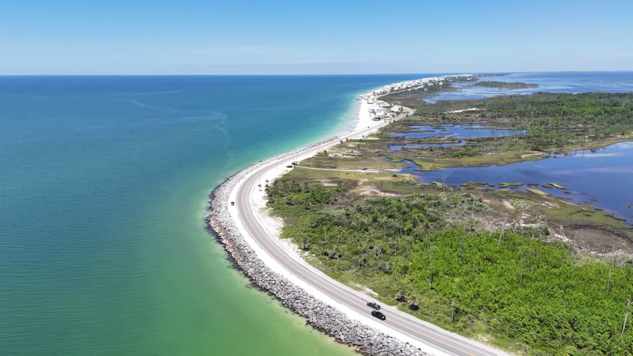 Panoramic drone fly at road of coastline with wetlands curving into turquoise seawater, Cape San Blas, Gulf County, Florida, USA