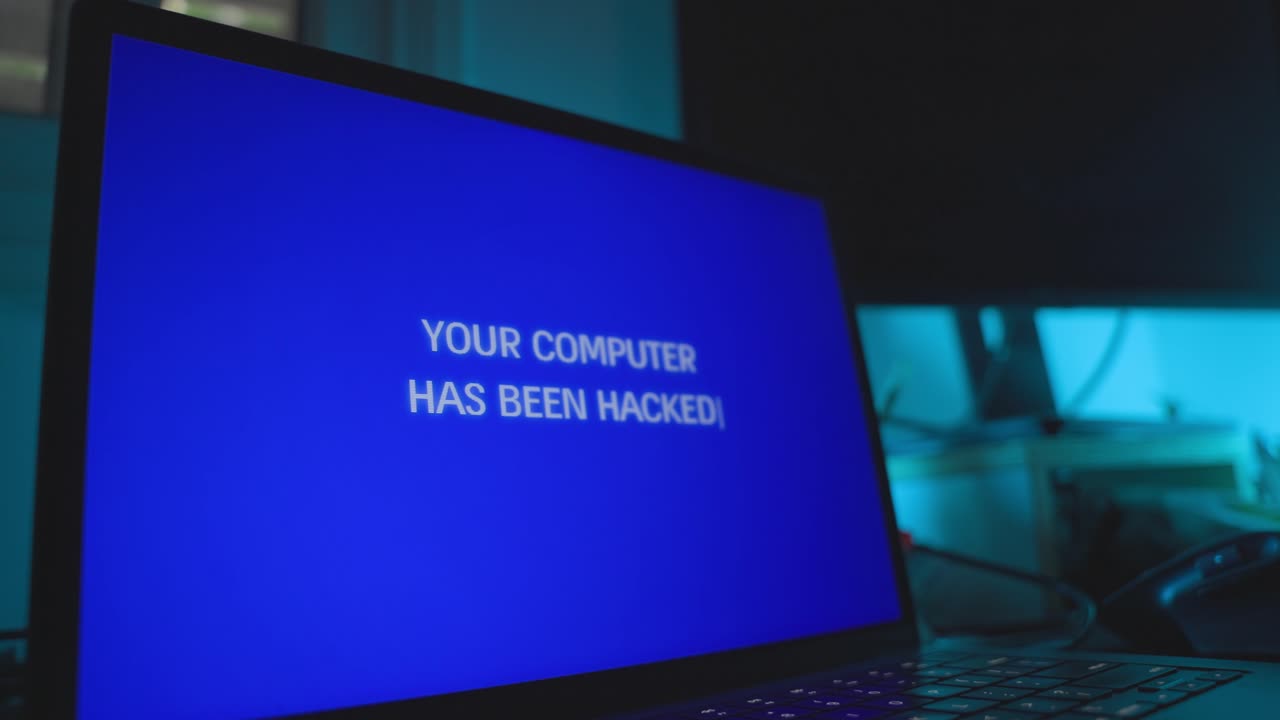 Computer screen in dark office is hacked remotely with alert message on screen. Glitch and error notification or warning of cyber attack taking control of laptop on desk. Hacker group stealing data