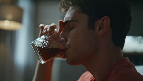 lonely alcoholic sipping bourbon at home closeup. hopeless man drinking alcohol