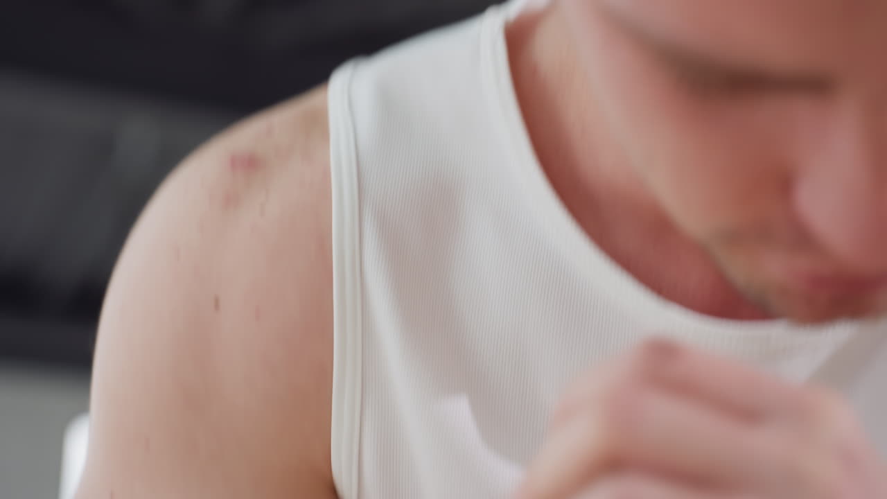 Close up of fair skinned man heads down hands clasped performing warm-up exercise in bright gym studio with modern ceiling lights highlighting intense focus and preparation for training
