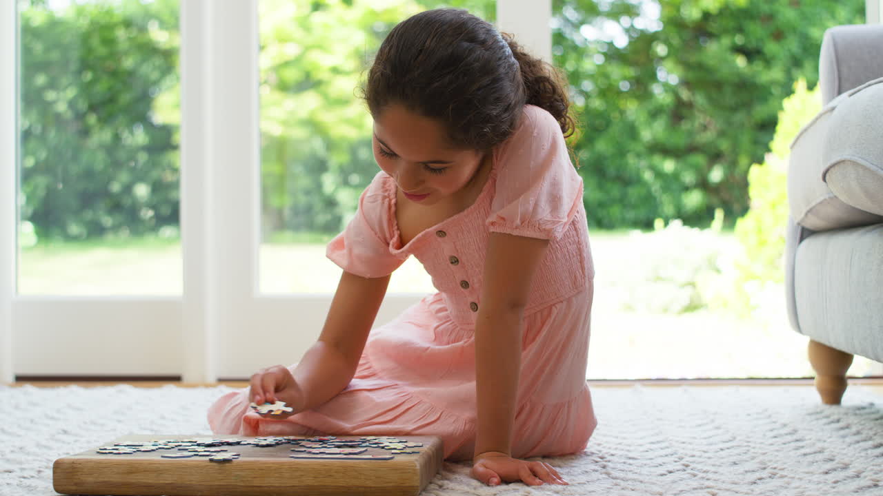 집에서 라운지의 바닥에 앉아 있는 소녀가 퍼즐을 하고 있습니다.