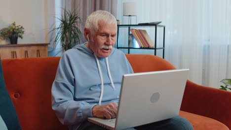 hombre sentado en el sofá de casa, mirando a la cámara, haciendo una llamada de videoconferencia con amigos o familiares