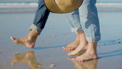 young caucasian couple walking barefoot along the shore