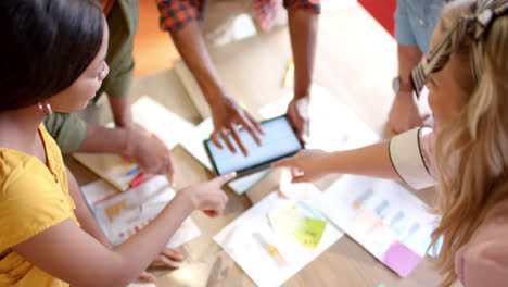 High-angle-of-happy-diverse-colleagues-brainstorming-with-tablet-in-office,-slow-motion