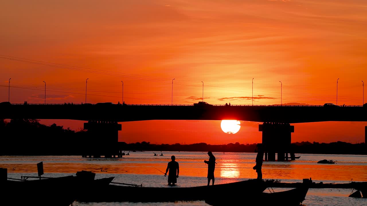 Silhouette of Fishermen Fishing at Sunset Under a Bridge
