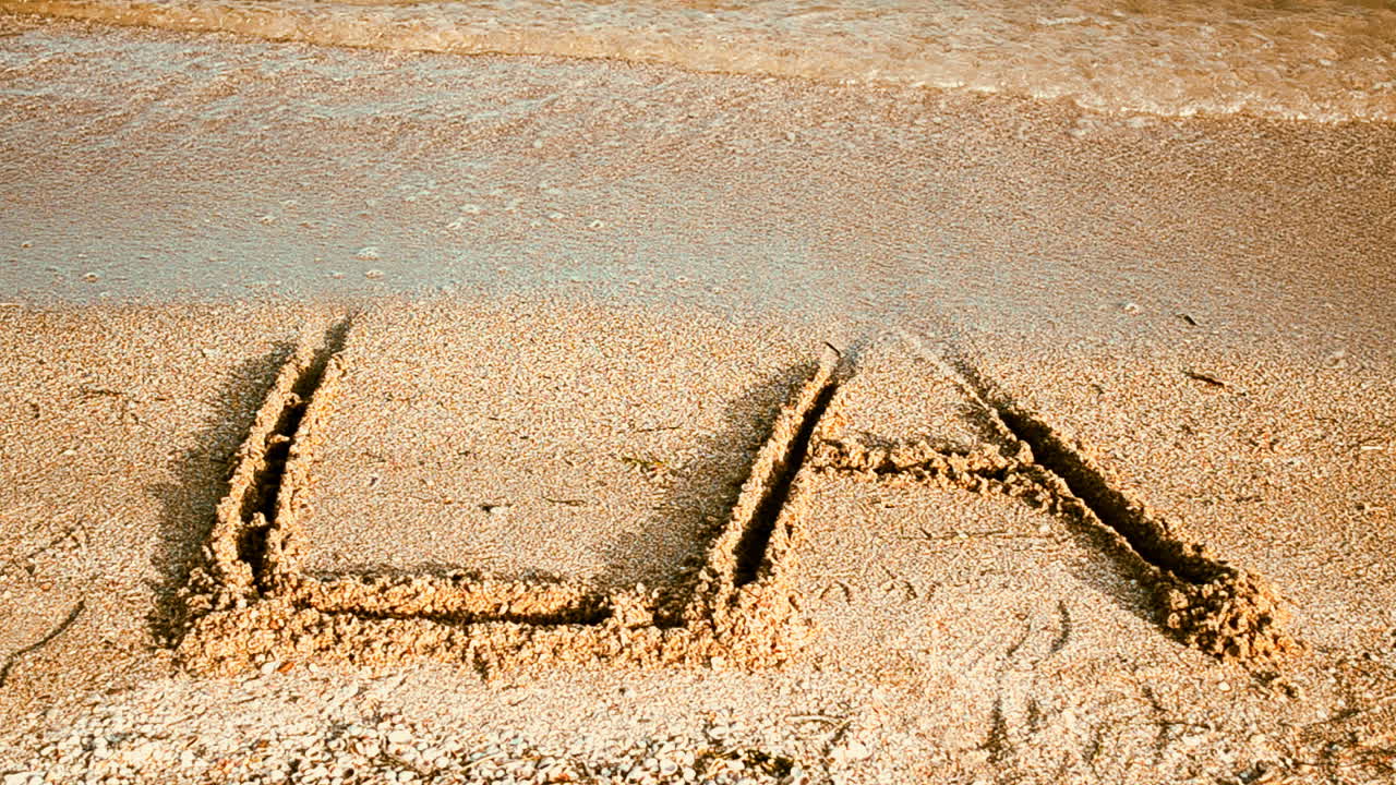 Inskriptionen LA på sand. Inskription på sand, stranden
