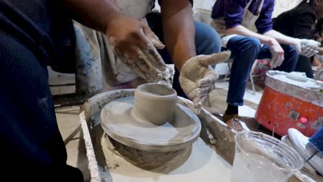 overhead close view of an african american hands spinning clay very sporadically while taking a pottery class in the city