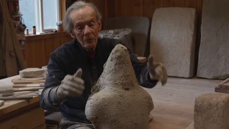 elderly man sculpting with clay in a workshop