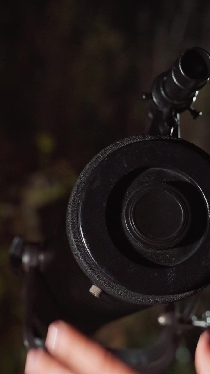 Ringed fingers interact with dark textured apparatus. Black object features textured edge with central hole. Primary focus is circular opening and hand device interaction