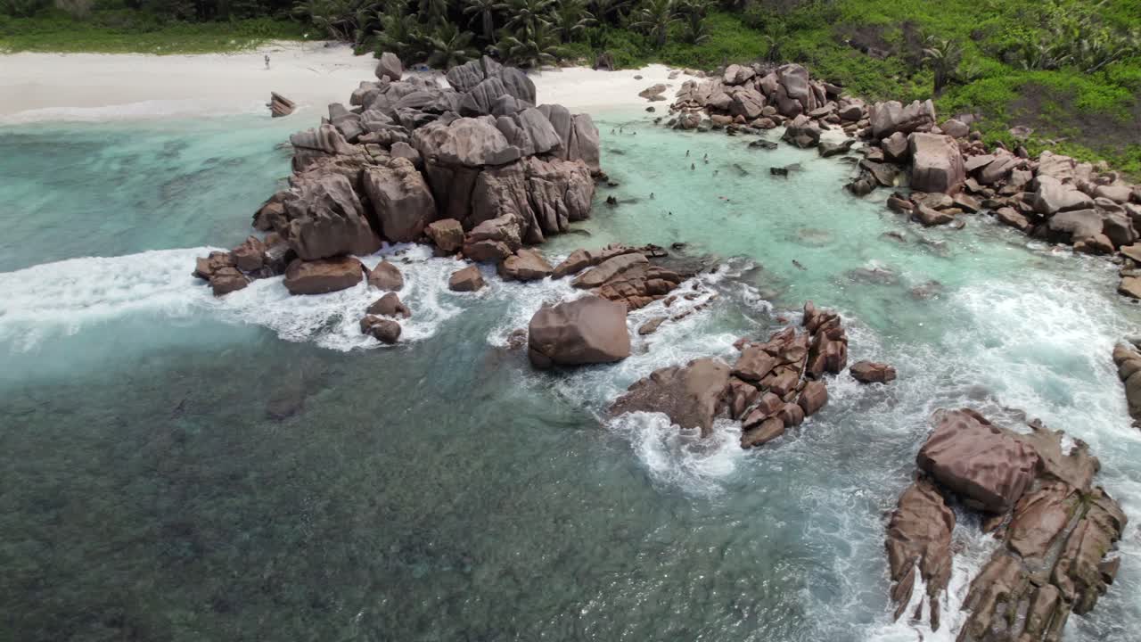 Vue par drone en recul de rochers de granit près du rivage, eau turquoise claire, personnes faisant de la plongée avec tuba, plage de sable blanc, Anse Cocos, La Digue, Seychelles 011.