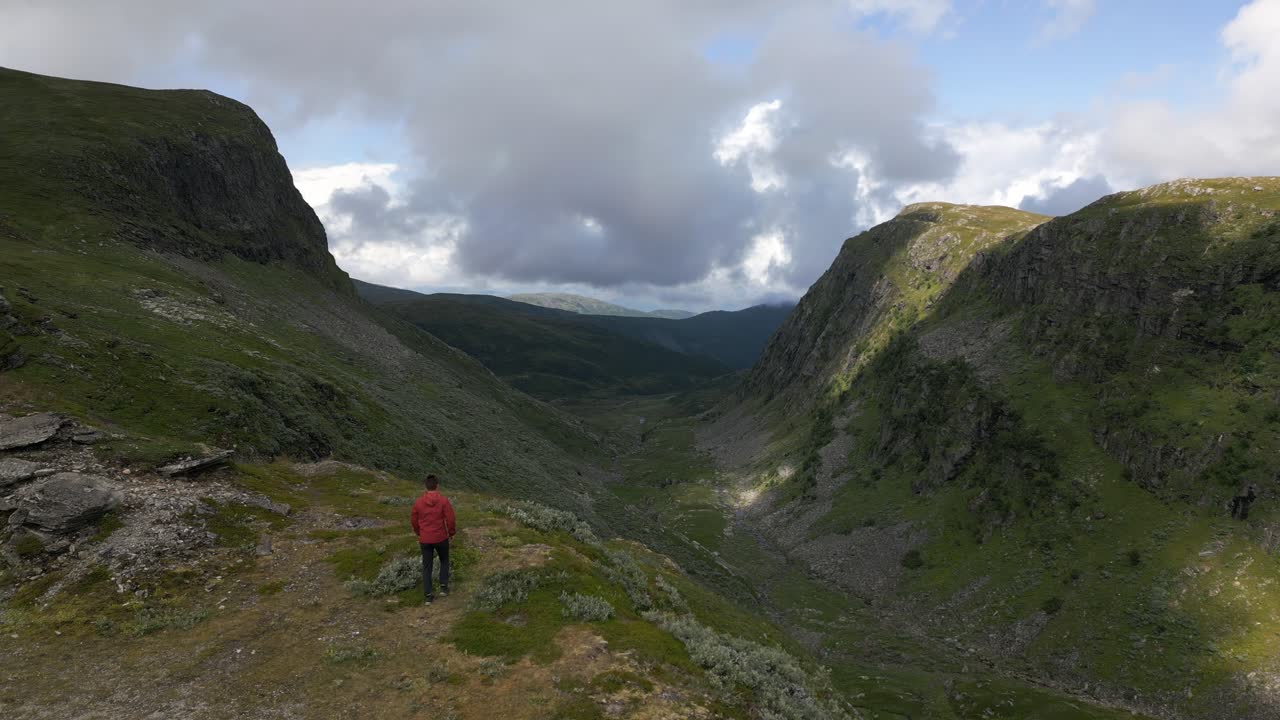 hombre que se acerca al acantilado con una majestuosa vista de un valle en vikafjell, noruega