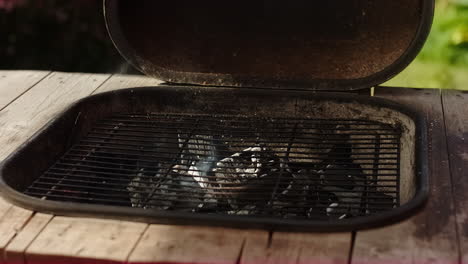 burning coal smoking on a bbq or barbecue grill in sweden on a warm summer day