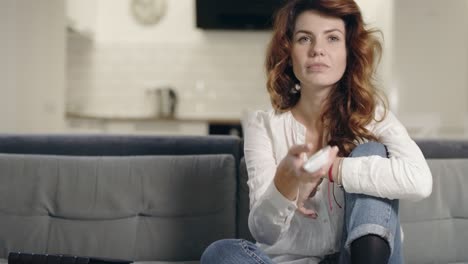 mujer concentrada sentada en el sofá en la cocina. chica emocionada de primer plano viendo la televisión