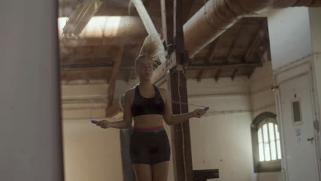 medium shot of beautiful woman jumping rope alone in gym