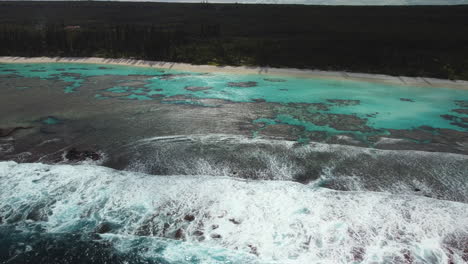 Toma-Aérea-De-Olas-Rompiendo-Sobre-El-Arrecife-En-La-Playa-Apartada-De-Yejele,-Nueva-Caledonia