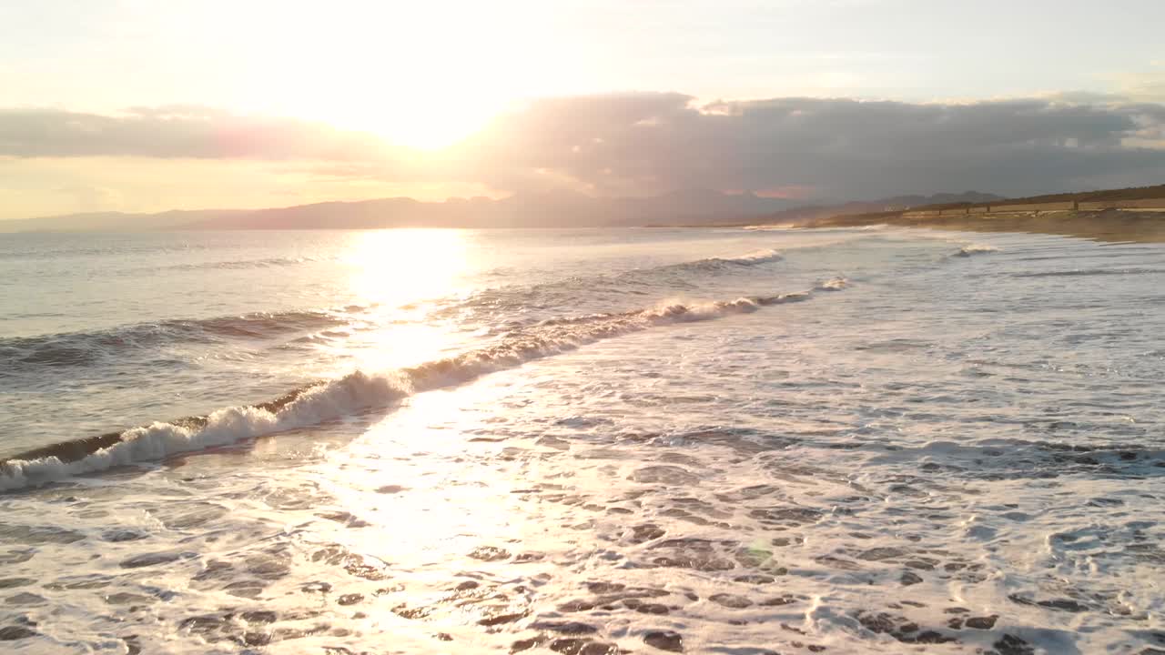 pov крупный план восходящего самолета над волнами, разбивающимися на пляже во время заката