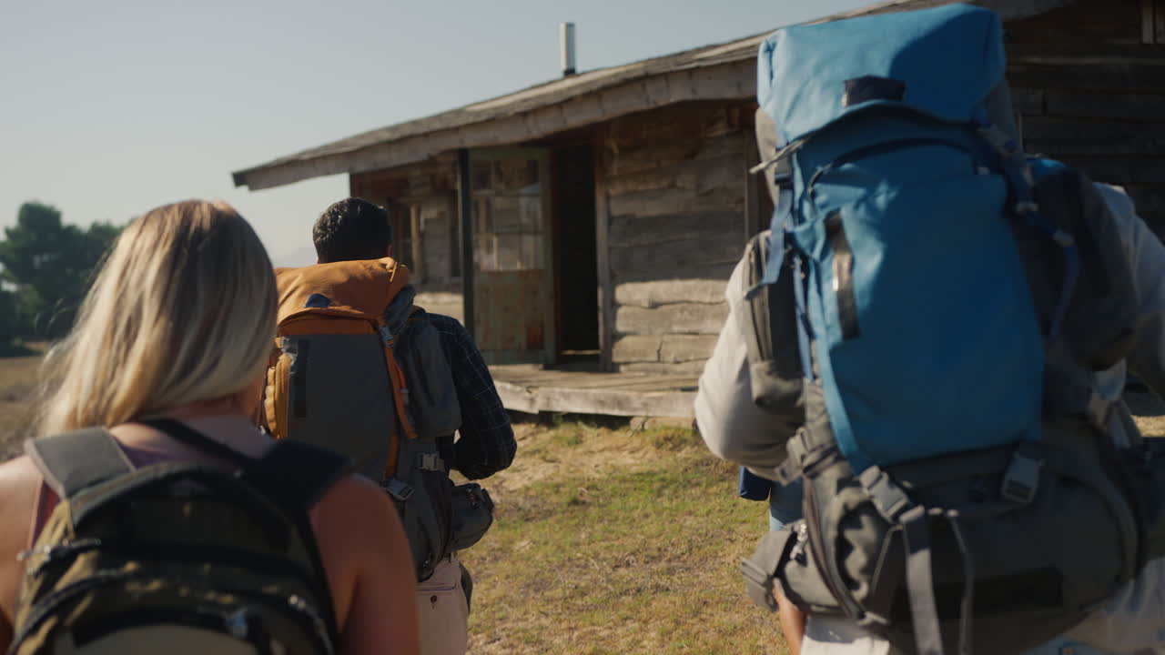 vista trasera de un grupo de amigos con mochilas caminando juntos en el campo