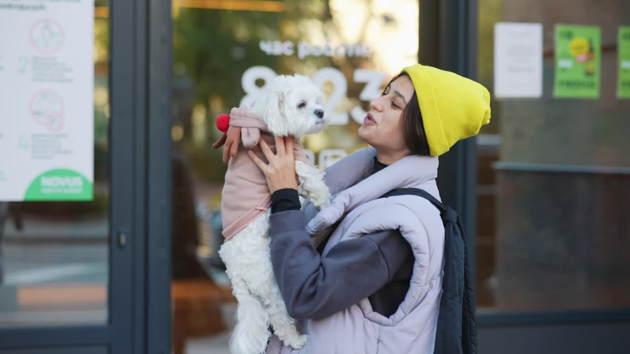 밖에서 작은 개를 들고 있는 여자