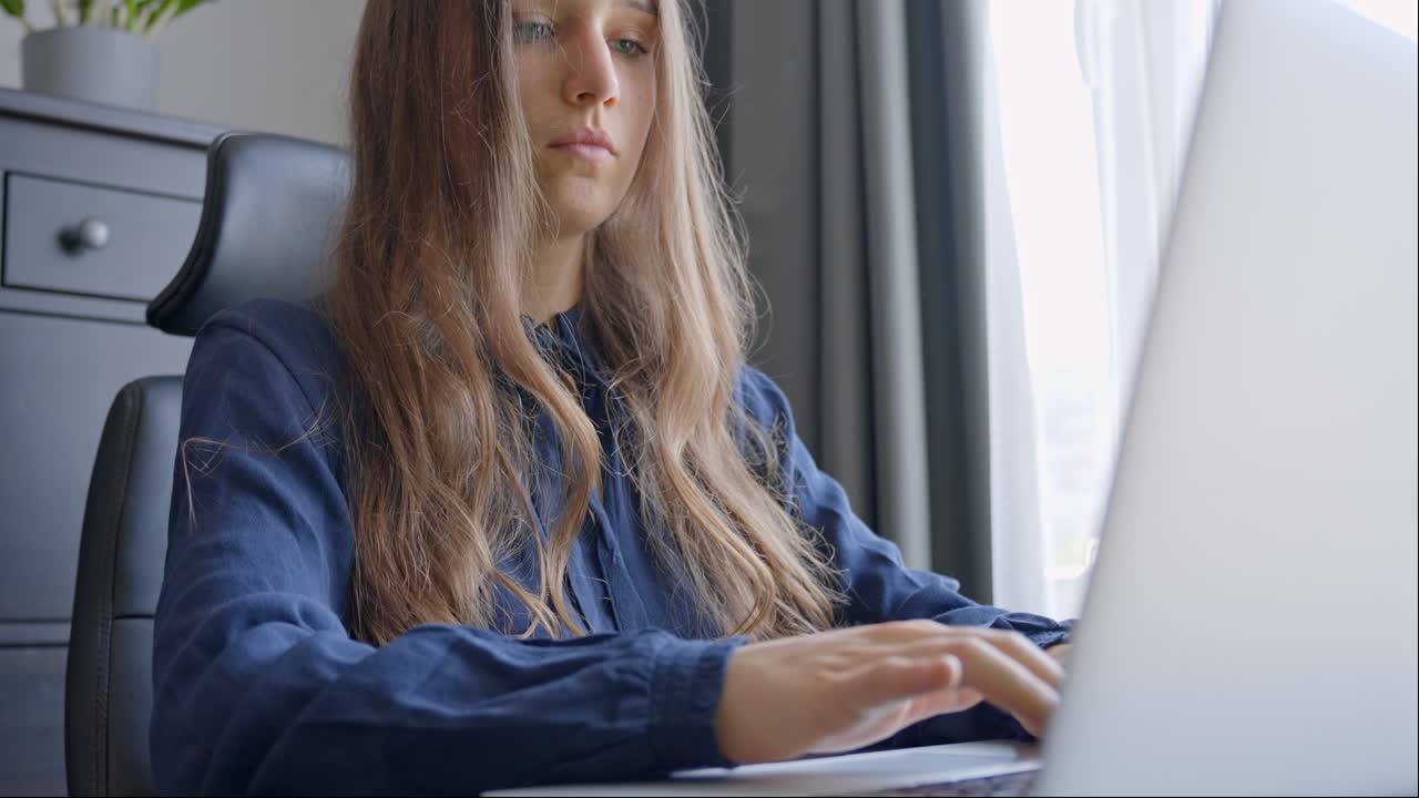 zoom hacia fuera de las manos de mecanografía a una joven mujer de negocios en el escritorio de casa