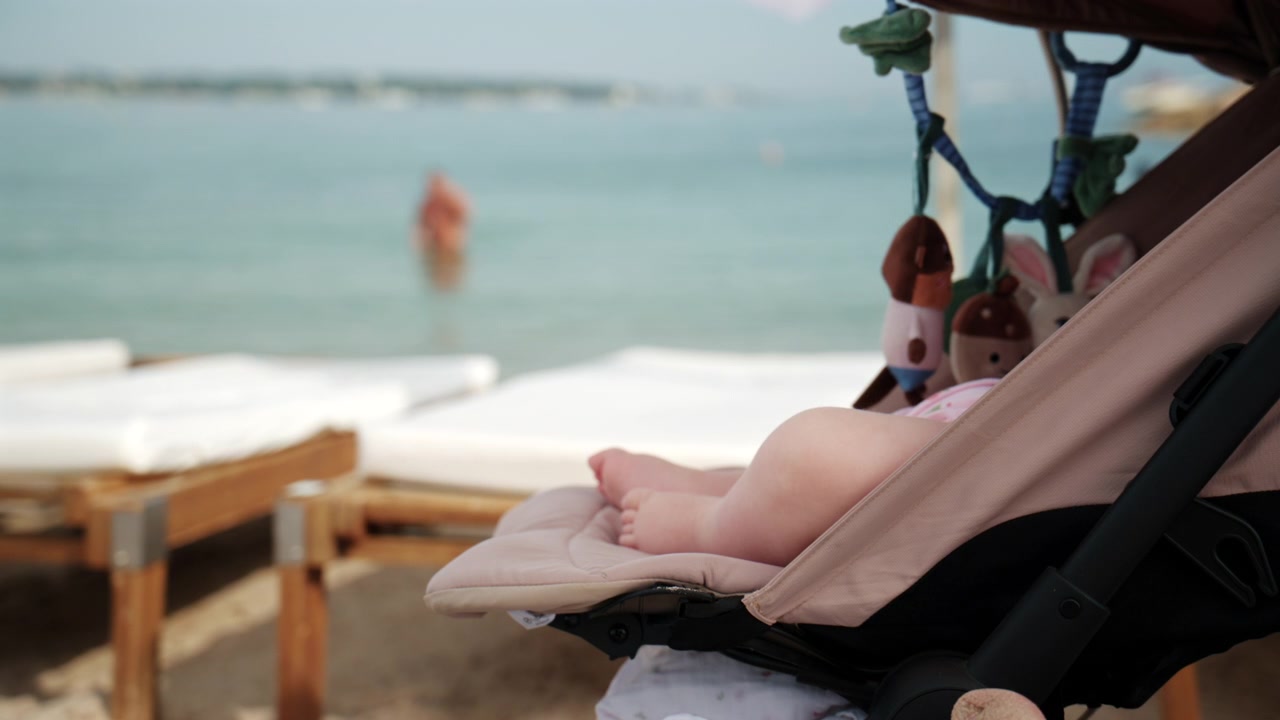 Scène de plage estivale paisible avec un bébé se reposant dans une poussette près d'une mer calme et de transats de plage