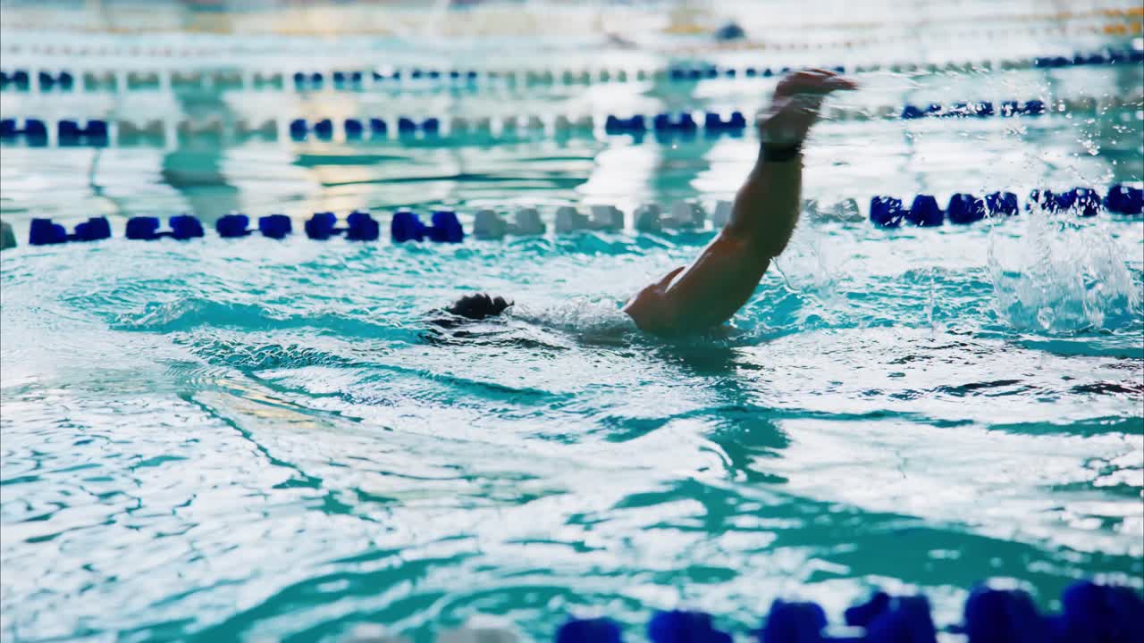 A swimmer propels through the clear, shimmering waters of a competitive swimming pool, showcasing athleticism and determination in a challenging race environment