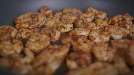 extreme close-up of seasoned shrimp frying in a pan