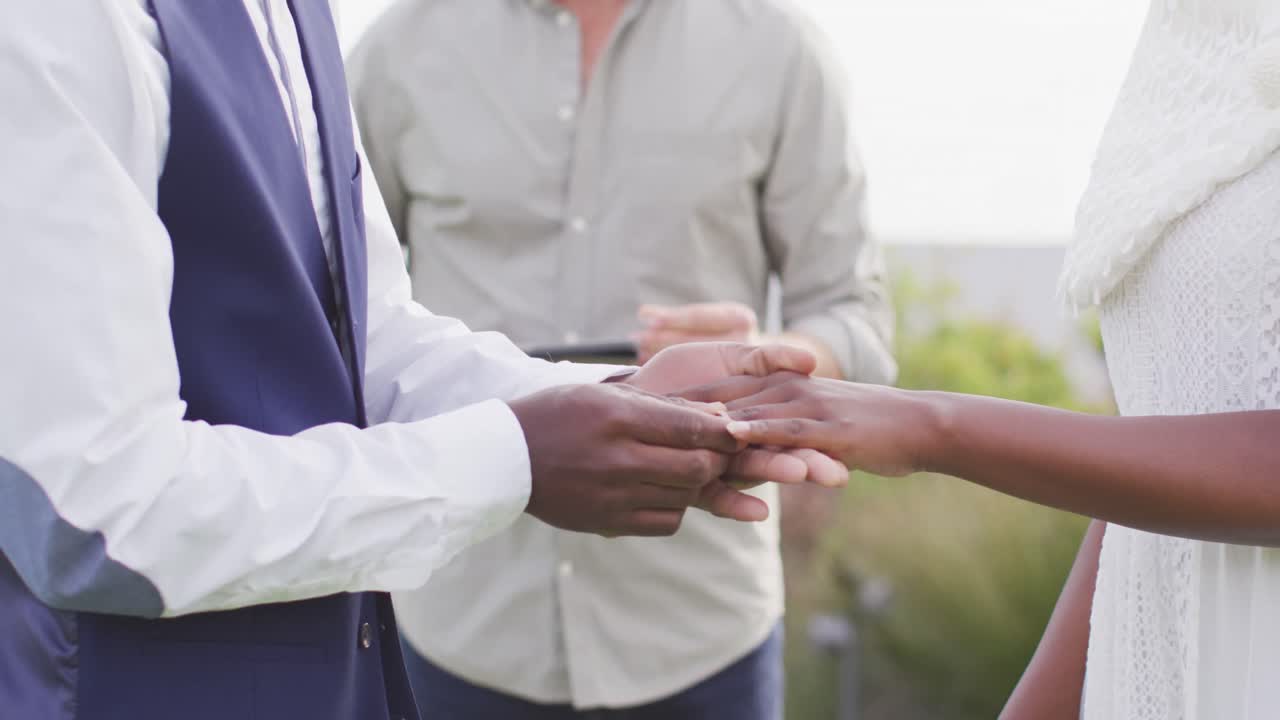 African american couple holding hands and putting ring during wedding