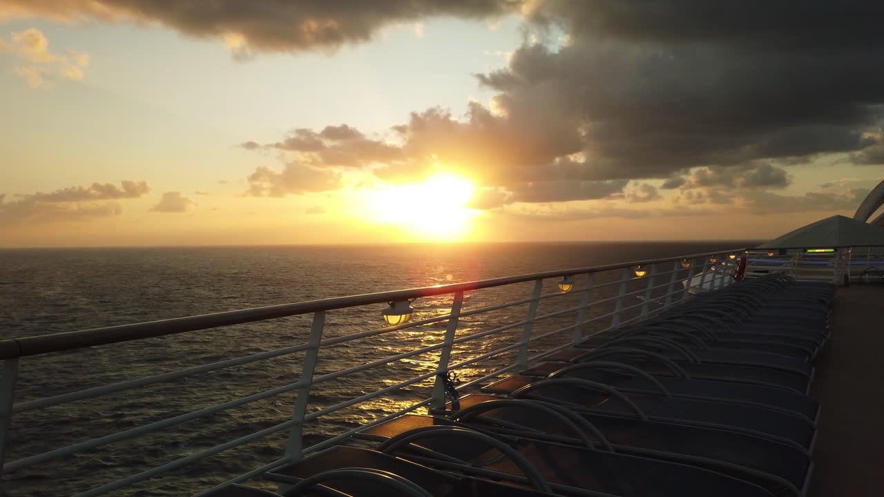 유람선의 난간을 따라 라운지 의자가 늘어선 바다 위의 놀라운 일몰