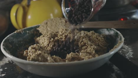 pouring delicious chocolate chips in batter -baking cookies -close up