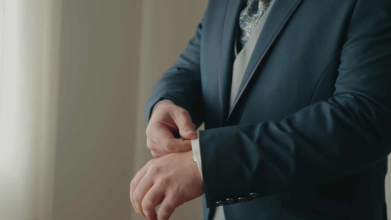 Primo piano dello sposo che sistema la manica e il polsino della giacca prima della cerimonia