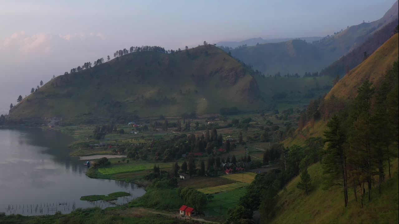 imágenes aéreas de drones de un pueblo frente al mar en el lago toba al pie de las montañas en el norte de sumatra, indonesia