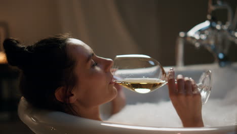 mujer pacífica bebiendo vino en un baño de lujo de primer plano. mujer relajada disfrutando del spa