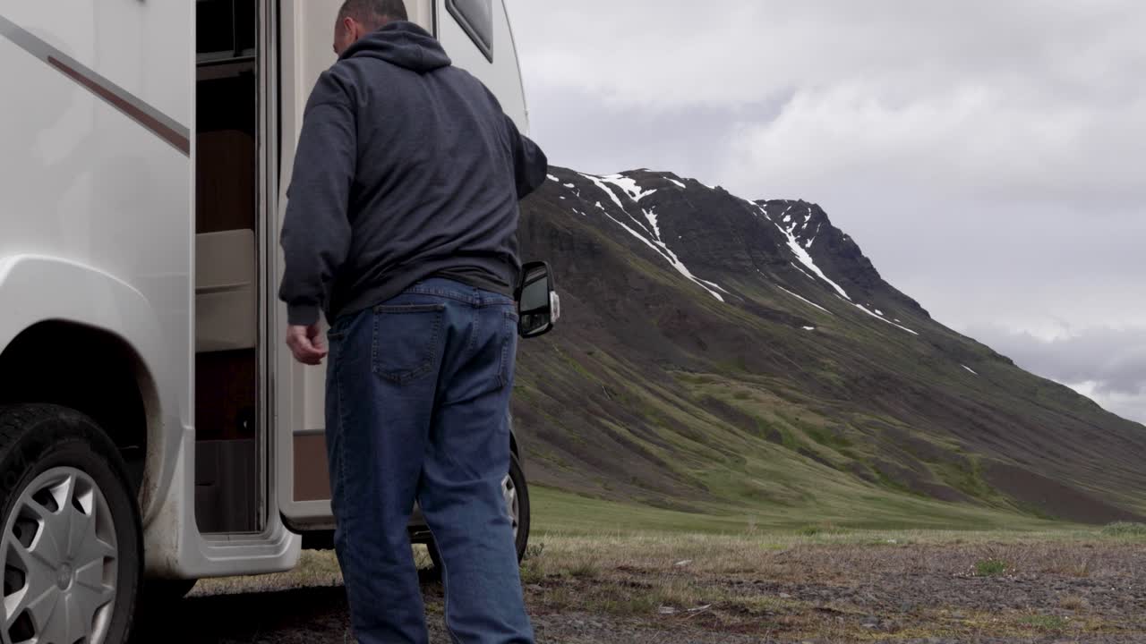 Uomo che cammina verso un camper in Islanda con una montagna