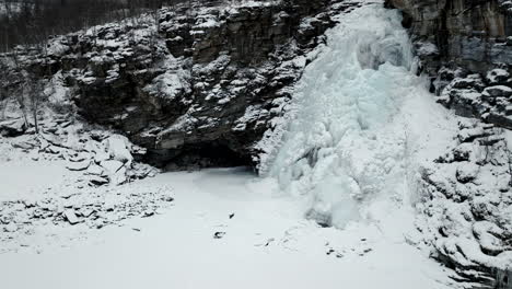 monochrome of a frozen waterfall flowing from rocky cliffs during winter in northern, norway