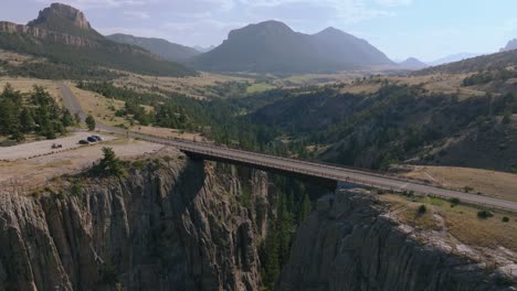 drone pullback over sunlight creek bridge in wyoming, revealing the stunning surrounding canyon and distant mountain range