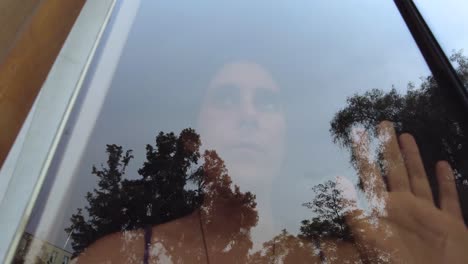 sad young woman behind a glass window, feeling trapped concept, under quarantine, suffering from depression, lockdown.