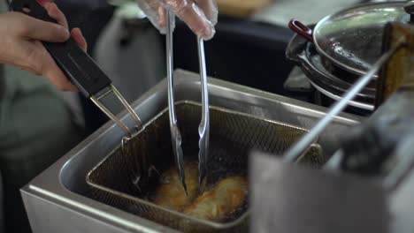 Bread-rolls-deep-fried-in-vat-of-boiling-hot-oil,-filmed-as-close-up-shot-in-handheld-slow-motion-style